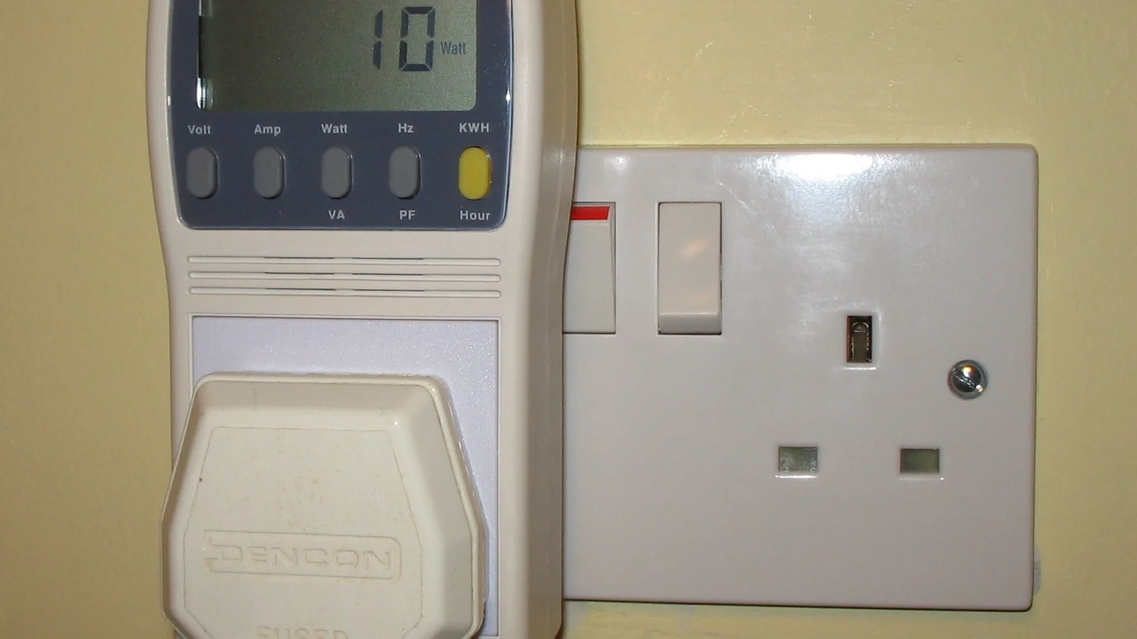 A plug-in electricity monitor connected to a UK wall socket.